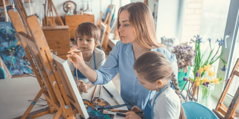 Une femme et deux enfants qui peignent sur une toile